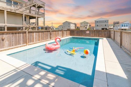 a swimming pool with a pink flamingo in the water at Carolina Kai, Kitty Hawk MP 3, 275 Yds to Beach, Ocean View, Pool, Hot Tub, Flex Stays in Kitty Hawk