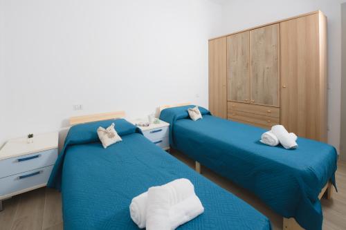 two beds in a room with blue sheets and towels at Villetta Caterina in Procida