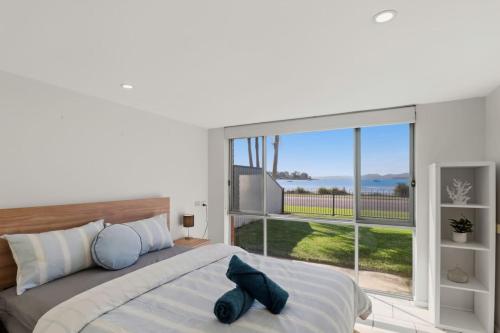 a bedroom with a large bed and a large window at Bayview Nook Tanilba Bay in Lemon Tree Passage