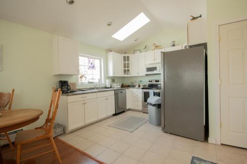 a kitchen with white cabinets and a stainless steel refrigerator at Walk to Willard Beach in South Portland