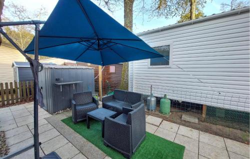 a patio with a blue umbrella and chairs and a table at Lovely Stacaravan In La Tremblade in La Tremblade