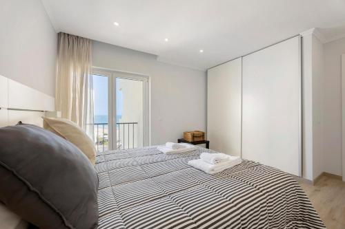 a bedroom with a large bed with a large window at Casinha da Praia da Rocha in Praia da Rocha