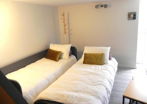 two beds in a room with white sheets and gold pillows at Le Gîte Du Vigneron in Saulcet