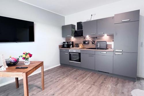 a kitchen with gray cabinets and a wooden table at Emsland-Hus WG2 in Niederlangen