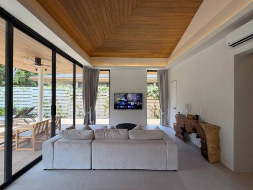 a living room with a white couch and large windows at MoonLight Villa - 3BR Tropical Pool Retreat in Ko Phangan