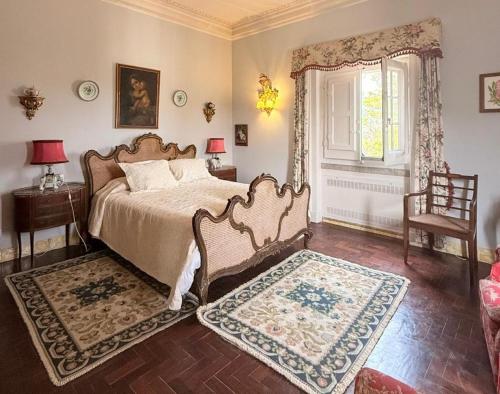 a bedroom with a bed and a chair and a window at Quinta de Sao Thiago in Sintra