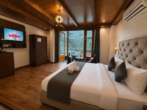 a bedroom with a large bed and a television at Hotel Asiia Holiday with Swimming Pool -Central Heated and Air Cooled, Near mall road in Kasol