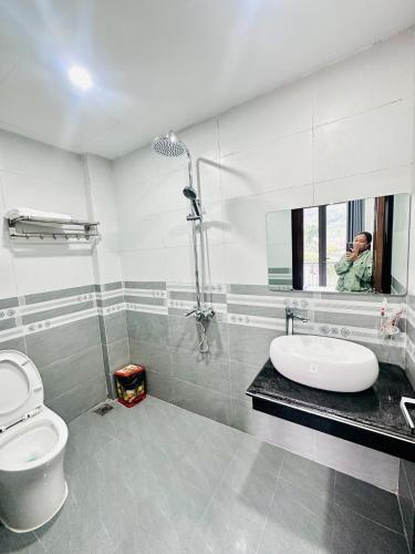 a man taking a picture of a bathroom with a toilet and sink at Mộc Hưng Homestay in Bắc Hà