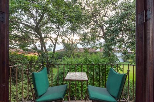 two green chairs and a table on a balcony at Hotel Museo Spa Casa Santo Domingo in Antigua Guatemala
