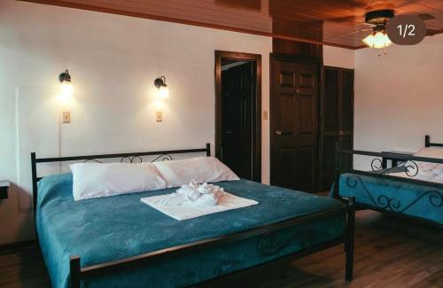 a bedroom with a bed with a blue blanket and flowers on it at Hotel Central Boquete in Boquete