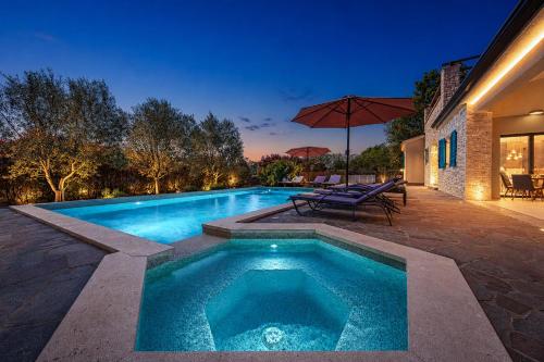 a swimming pool with a table and an umbrella at Villa Martha in Central Istria with private pool - wellness & table tennis for 12 persons in Žminj