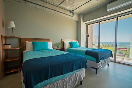 two beds in a room with a view of the ocean at Pacific Surfside Ocean Views in Surf City in ChiltiupÃ¡n
