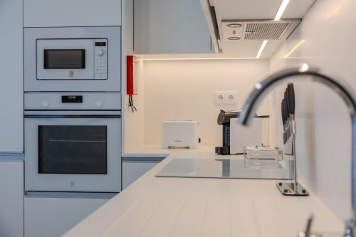 a white kitchen with a sink and a microwave at Azor Signature Flats - I in Ponta Delgada