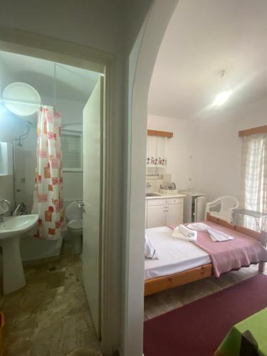 a bedroom with a bed and a bathroom with a sink at Apartments MOYRKOS in Missolonghi