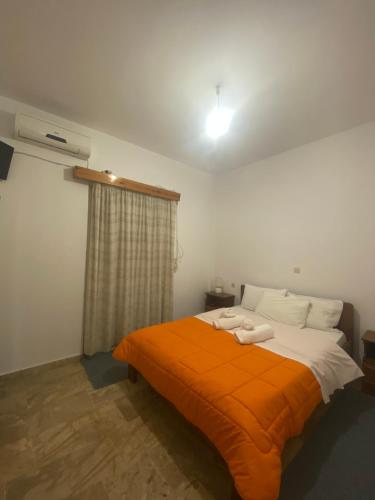 a bedroom with a bed with an orange blanket at Apartments MOYRKOS in Missolonghi