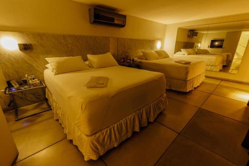 a hotel room with two beds and a mirror at Lemon Motel- Afogados in Recife