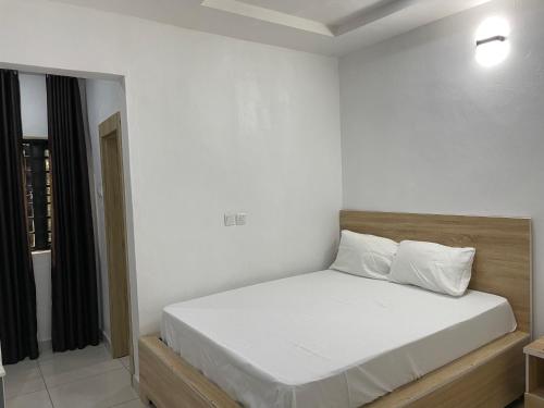 a bedroom with a bed with white sheets and a window at Lloyd Hotel and Suites in Benin City
