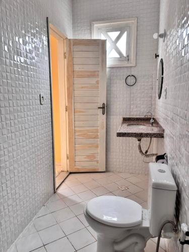a white bathroom with a toilet and a sink at Casa das Petúnias in Ubajara