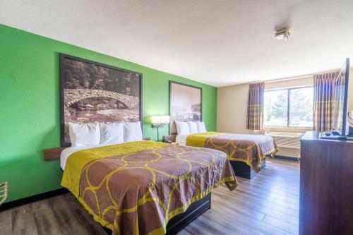a hotel room with two beds and a green wall at Super 8 by Wyndham Sioux City South in Sioux City