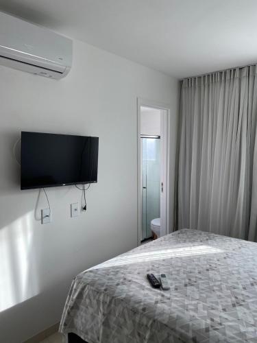 a bedroom with a bed with a flat screen tv on the wall at Refúgio Aconchegante & Charmoso! in Aracaju