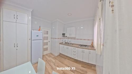 a white kitchen with white cabinets and a refrigerator at Apartamentos Bemar in Chipiona