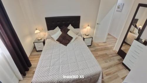 a bedroom with a large bed with two lamps at Apartamentos Bemar in Chipiona