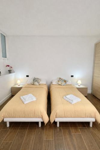 two beds in a room with wooden floors at Apt Pisces - Oasi di Menaggio in Menaggio