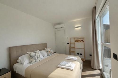 a white bedroom with a large bed and a window at Apt. Aquarius Oasi di Menaggio in Menaggio
