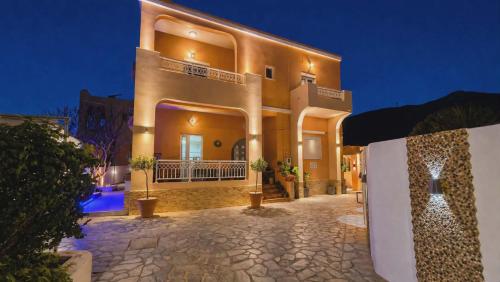 a large yellow house with a stone driveway at Papafotis Apartments & Suites in Alinda