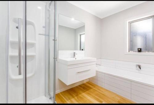 a white bathroom with a sink and a shower at Spacious One-Bedroom with Private Bathroom Aotea in Porirua