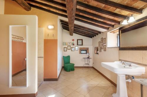 a bathroom with a sink and a green chair at Fattoria La Striscia in Gambassi Terme