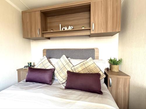 a bed with two pillows and a cabinet above it at Primrose View in Filey