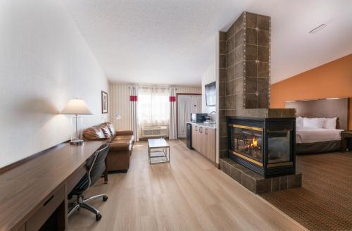 a hotel room with a fireplace and a bed at Prestige Prince George Lodge in Prince George