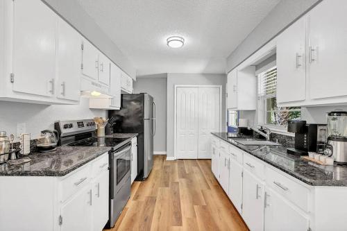 a large kitchen with white cabinets and wooden floors at Blue Spring Getaway with Fire Pit in Orange City