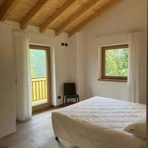 a bedroom with a bed and a chair and a window at Chalet in Pieve di Ledro-Ledrosee 57751 in Pieve Di Ledro