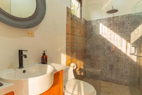 a bathroom with a sink and a toilet and a mirror at Selvática Residences in Puerto Viejo