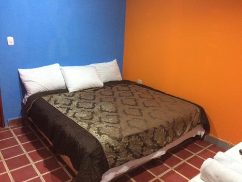 Cama en habitación con paredes azules y naranjas en Coco Blue Resort, en La Libertad