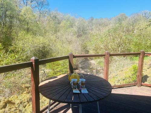a table with two glasses on top of a deck at Garden Cabin at Shengan in Banavie