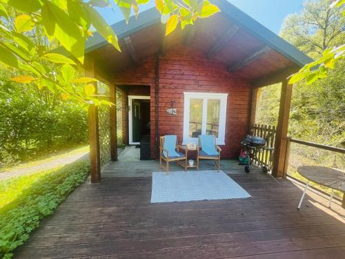 a porch of a red brick house with two chairs and a table at Garden Cabin at Shengan in Banavie
