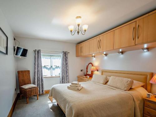a bedroom with a bed and a chair and a window at 3 Bed in Conwy oc-95906 in Conwy