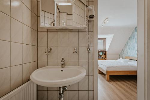 a bathroom with a white sink and a bedroom at Pension Haus Elmar in Rösrath