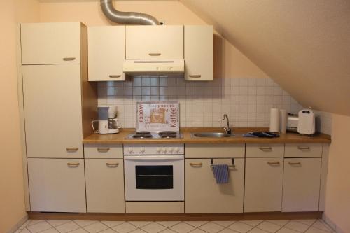 a small kitchen with white cabinets and a sink at Steenshof in Heringsdorf