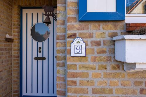 a blue door with a mirror on a brick wall at B&B Dreamcottage in Knokke-Heist