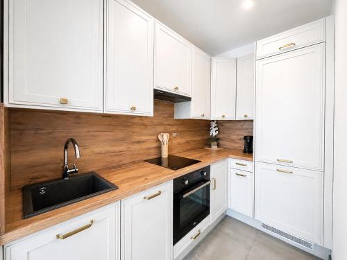 a white kitchen with white cabinets and a sink at Ami Luxury Residence XII CENTRUM - parking in Iława
