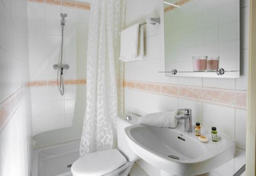 a white bathroom with a toilet and a sink at Antonios Hostal in Sitges
