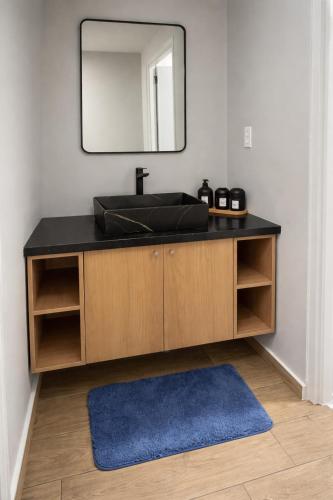 a bathroom sink with a mirror and a blue rug at Southgate Residence in Paramaribo