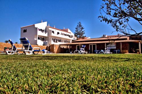 a house with two lawn chairs in a yard at Tonel Apartamentos Turisticos in Sagres