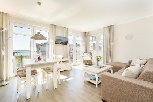 a white living room with a table and a couch at Haus Vogelflug strandleev3 in Fehmarnsund