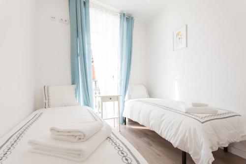 a white bedroom with two beds and a window at White Tiles in City Center in Lisbon