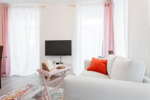 a white living room with a white couch and a tv at White Tiles in City Center in Lisbon